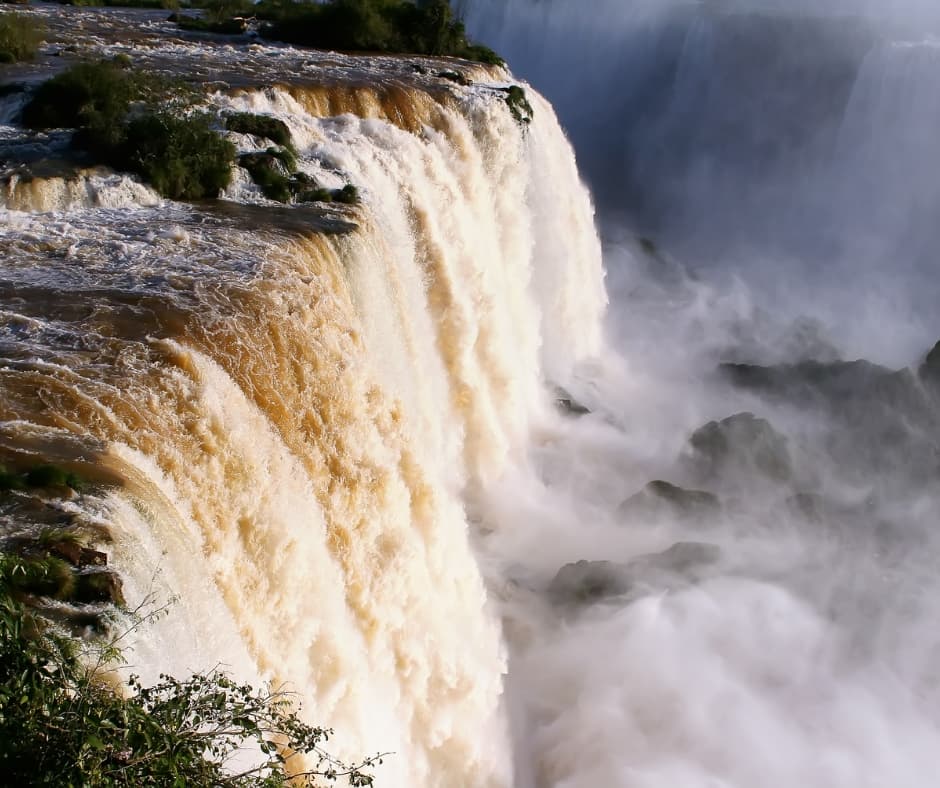 Rushing water cascades over a rocky ledge, creating a thick mist below